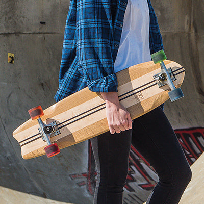 Person holding a handcrafted wooden skateboard deck with visible wood grain and trucks.