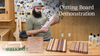 Woodworker holding a laminated wood cutting board with three finished cutting boards on the workbench.