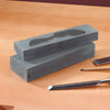 Two gray sharpening stones stacked with a chisel and a small flat tool on a wood surface