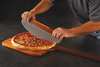 Hands using a wooden-handled pizza cutter on a pizza resting on a wooden pizza peel.