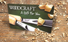 Woodcraft gift card surrounded by wood shavings and two carving gouges on a workbench