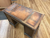 Duncan Phyfe-style writing desk with worn veneer and finish in workshop setting.