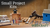 Woodworking small project kits including cutting boards, pens, carving tools, and a birdhouse on a workbench