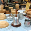 Woodturned wooden vessels and metal spinning projects displayed on workshop table.