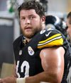Man in Pittsburgh Steelers football jersey in a workshop with woodworking tools blurred in background