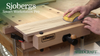 Hand sanding wooden slats clamped on Sjobergs Smart Workstation Pro with bench vise visible