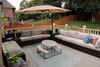 Outdoor deck with composite decking, cushioned wicker seating, umbrella, and decorative rug in backyard setting