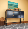 Black painted wooden sideboard with turned legs, drawers, and carved door panels in a home setting