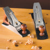 Two metal and wood hand planes on a workbench with wood shavings around them