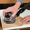 Hand using a Porter-Cable random orbital sander on a wooden board with dust collection hose attached