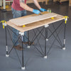 Applying finish to a wooden panel supported on a portable workbench with clamps and stands
