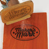 Wood branding iron burning Maker's Mark logo onto a smooth wooden board surface