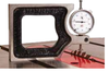 Dial indicator mounted on a square measuring the flatness of a table saw surface.
