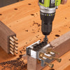 Drill driving screws into a jig aligning dowel joinery on walnut wood pieces.
