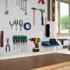 Pegboard wall with hand tools including hammers, pliers, screwdrivers, cordless drill, and tape in a woodworking shop setup.