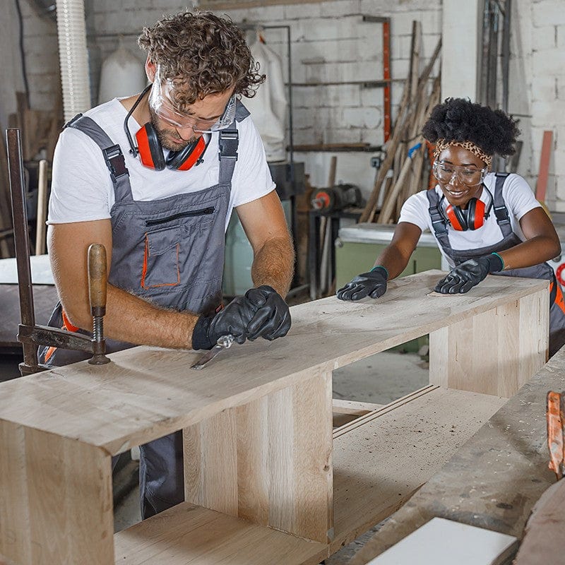 Two people working on a wooden bench in a workshop.